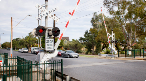 A level crossing with the boom barriers raising